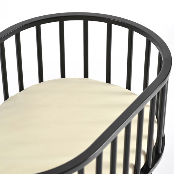 Black wooden baby bassinet with curved oval frame and elevated nursery design