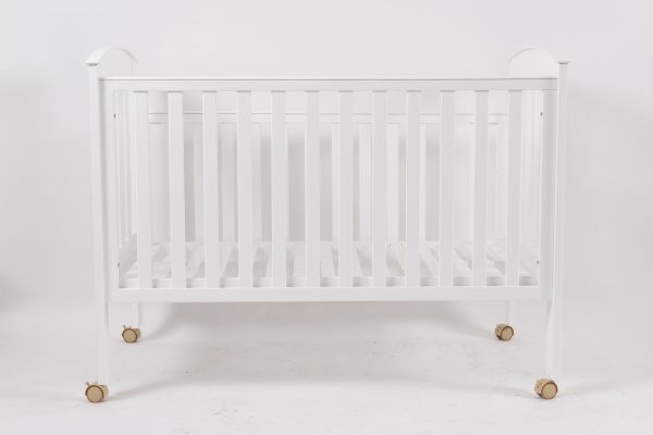 Front view of white wooden baby crib with wheels