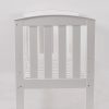 End view of white wooden baby crib with curved panel