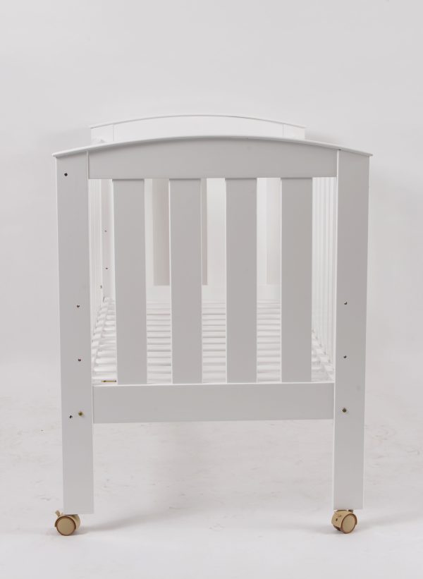 End view of white wooden baby crib with curved panel