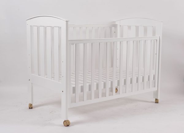 White wooden baby crib with lowered side panel and wheels