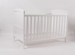 Angled view of white convertible baby crib with slatted side panels